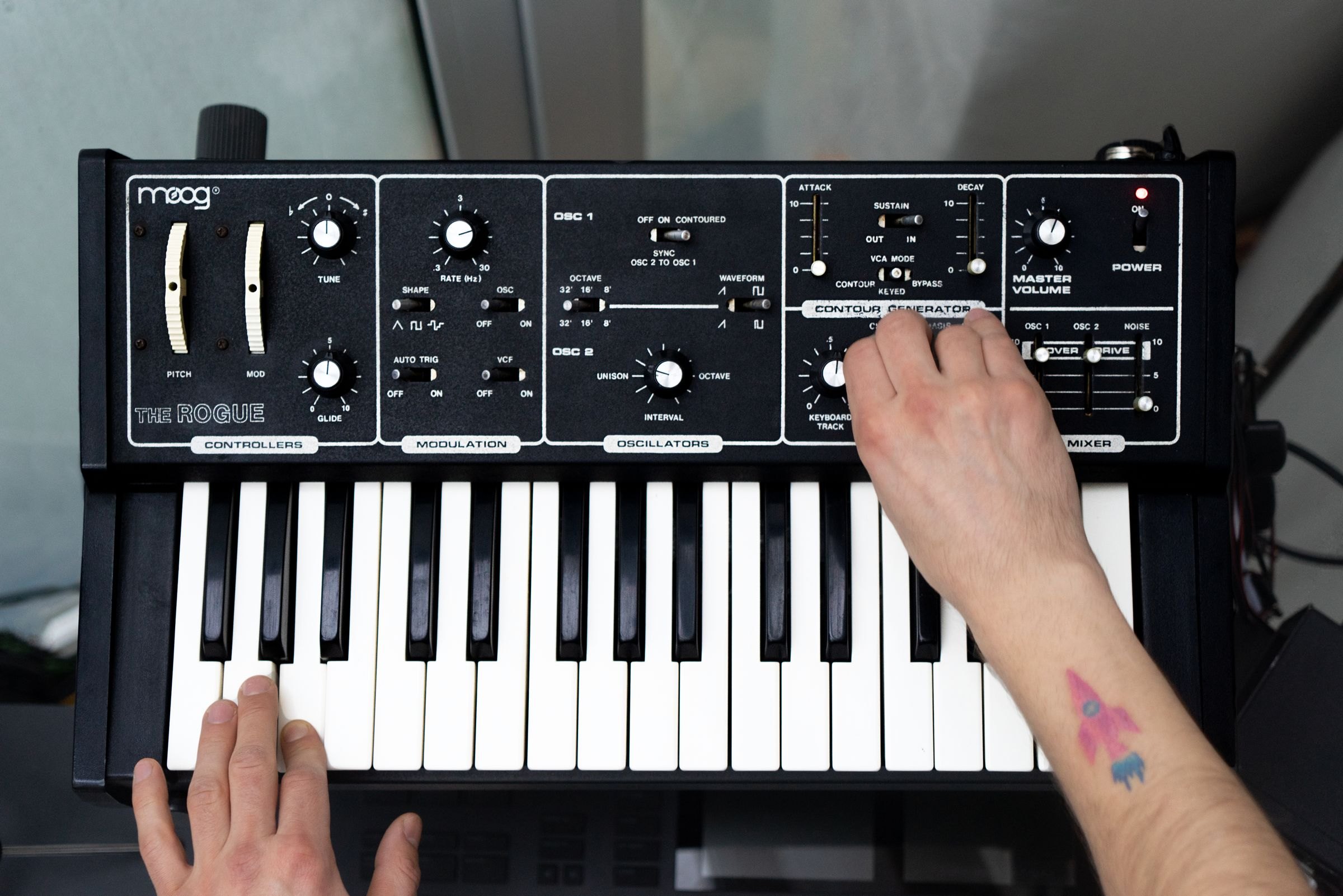 Hände spielen auf einem analogen Synthesizer mit vielen Reglern