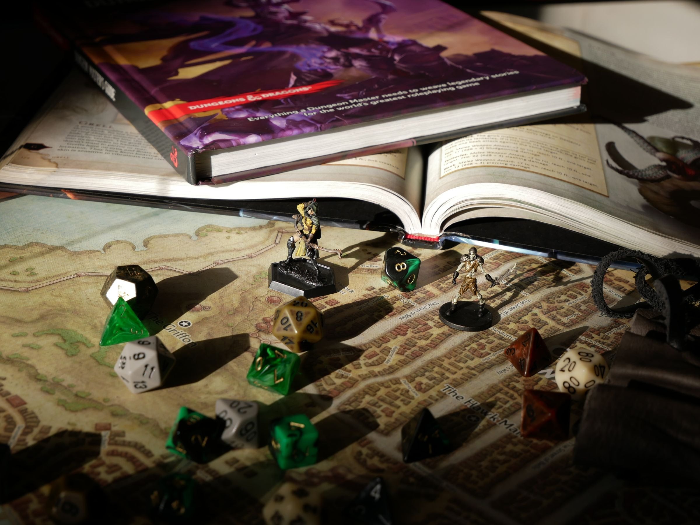 Spieltisch mit Regelbüchern, Würfeln und Figuren auf einer ausgebreiteten Landkarte